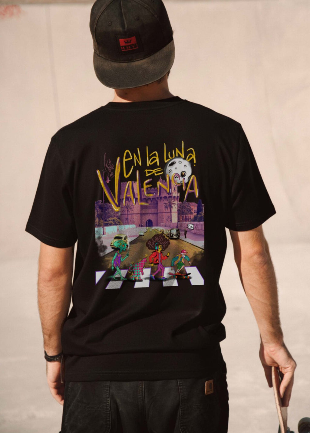 Hombre con camiseta unisex “En la luna de Valencia” negra, vista de espalda. Diseño artístico impreso en algodón orgánico de alta calidad.