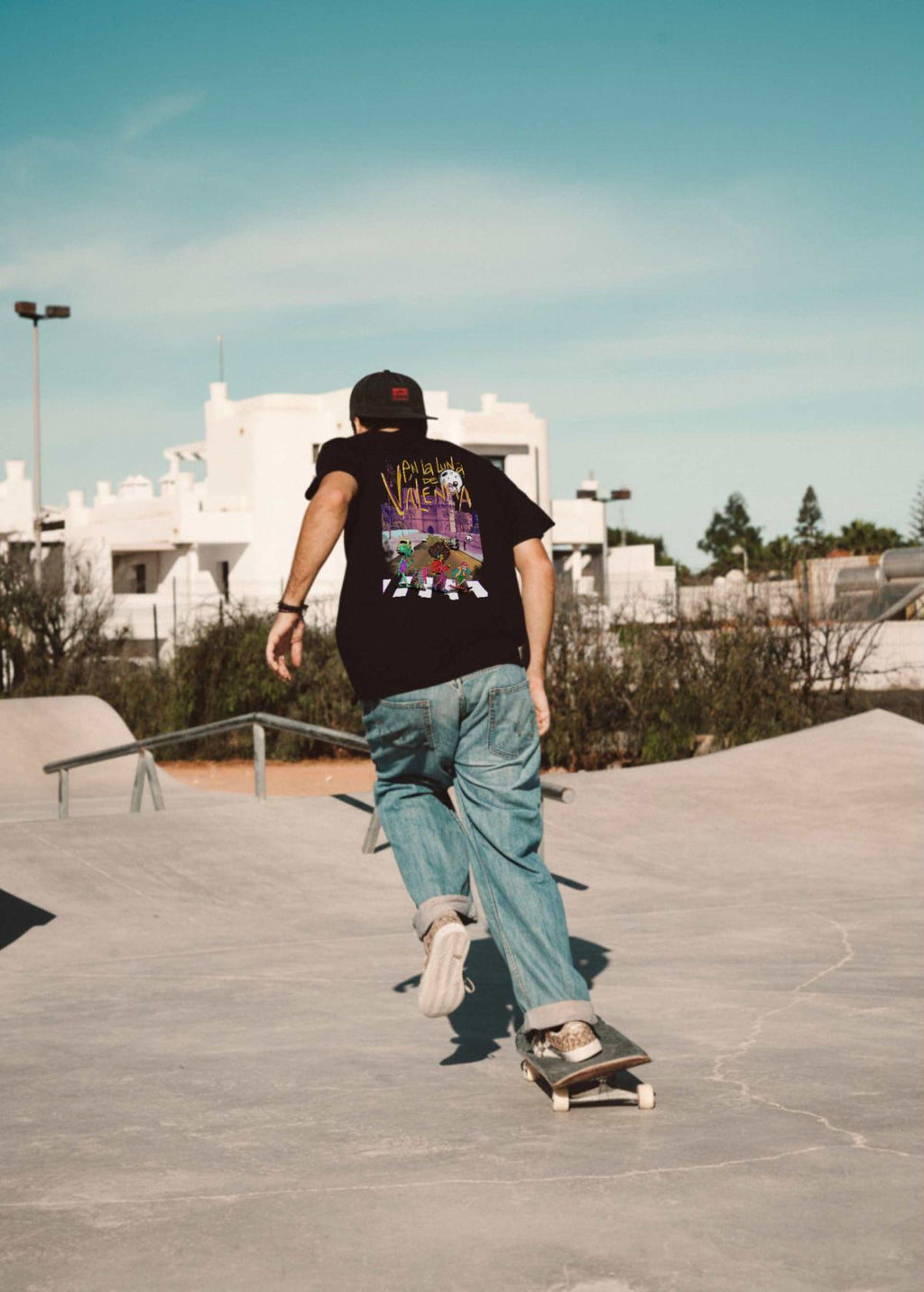 Skater con camiseta unisex “En la luna de Valencia” negra, vista de espalda. Diseño artístico impreso en algodón orgánico de alta calidad.