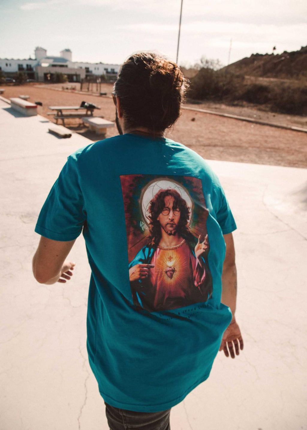 Hombre con camiseta unisex “John Jesus” color Ocean Depth, vista de espalda. Camiseta orgánica con diseño de arte digital LA GALLO ART.