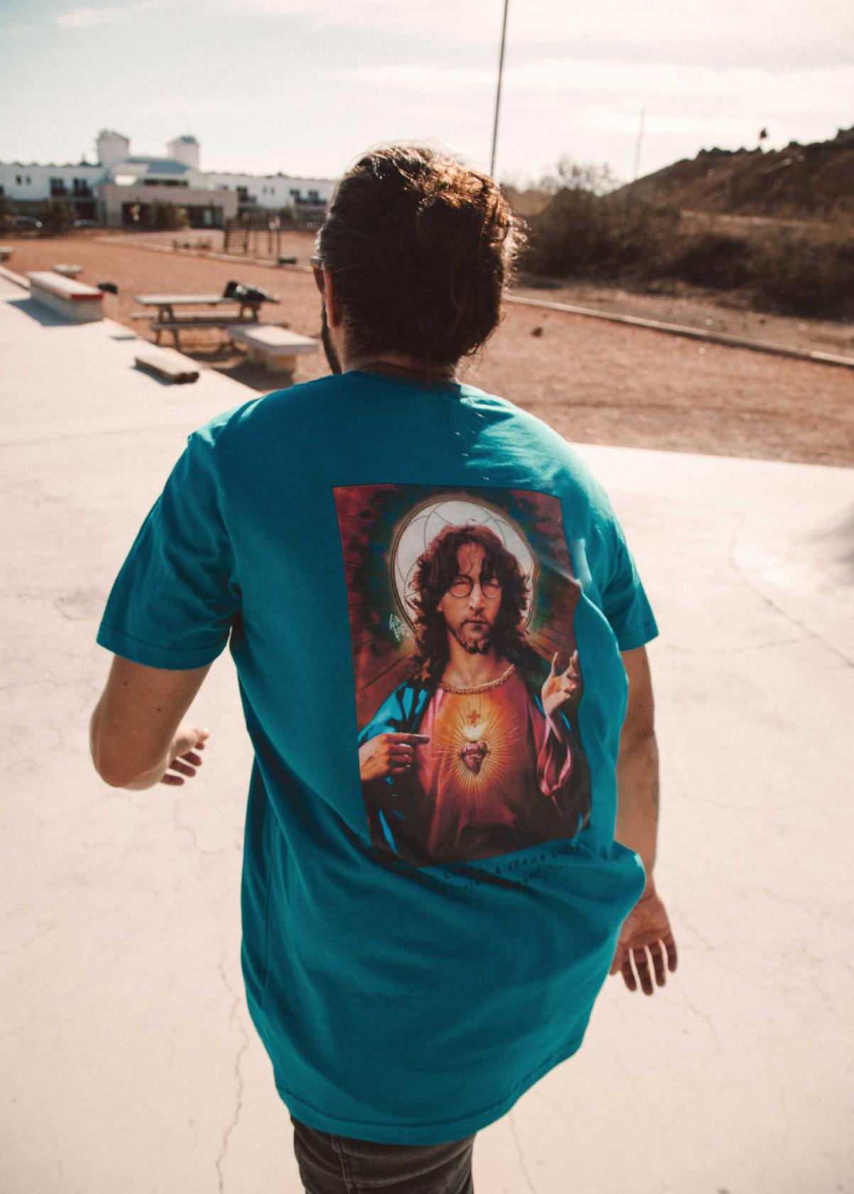 Hombre con camiseta unisex “John Jesus” color Ocean Depth, vista de espalda. Camiseta orgánica con diseño de arte digital LA GALLO ART.