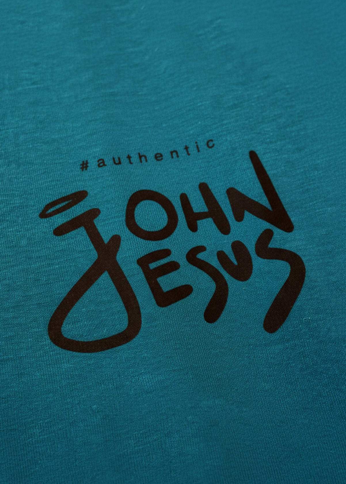 Detalle frontal del diseño “John Jesus” en camiseta unisex color Ocean Depth. Textura y colores del arte digital LA GALLO ART.