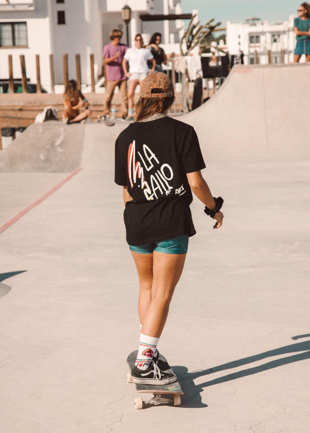 Mujer con camiseta “La Gallo Art” negra, vista de espalda. Logo de la marca impreso sobre algodón ecológico.