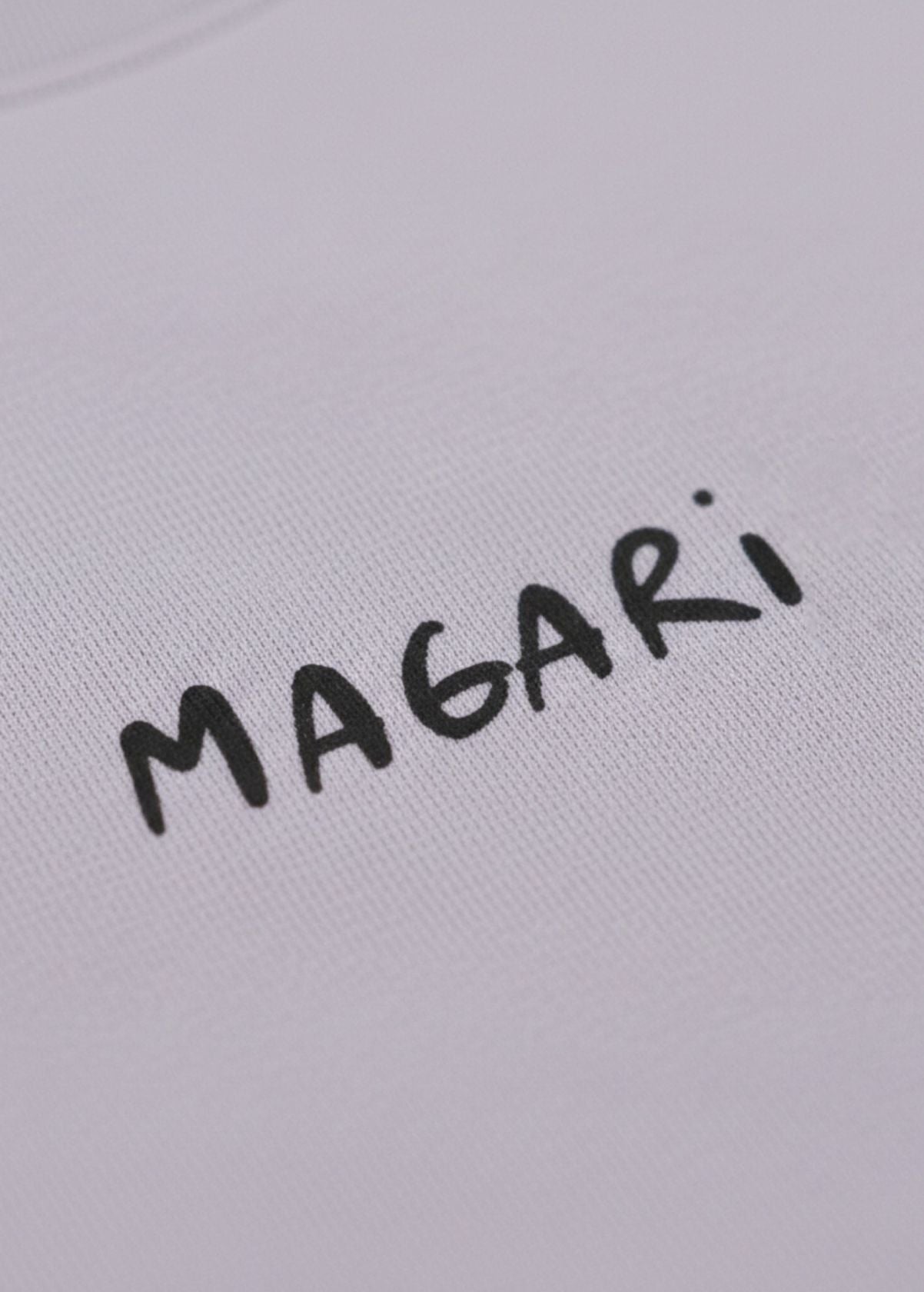 Detalle frontal del diseño “Magari” en camiseta color Lavender. Textura y acabado de impresión artística.