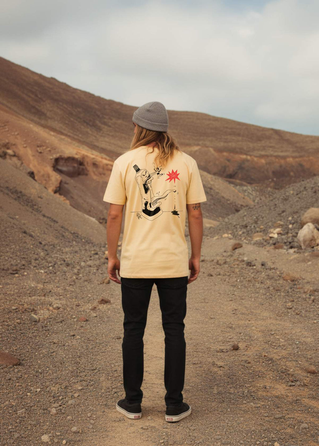 Hombre con camiseta unisex “Whisky” color Níspero, vista de espalda. Diseño artístico original impreso en algodón orgánico.